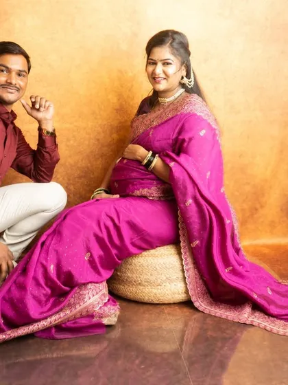 A lovely couple's portrait in traditional wear. The coordinated colors of the saree and the husband's shirt create a harmonious look.