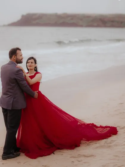 A romantic walk on the beach. The red trail gown flows beautifully behind the couple, creating a classic and timeless pre-wedding image.