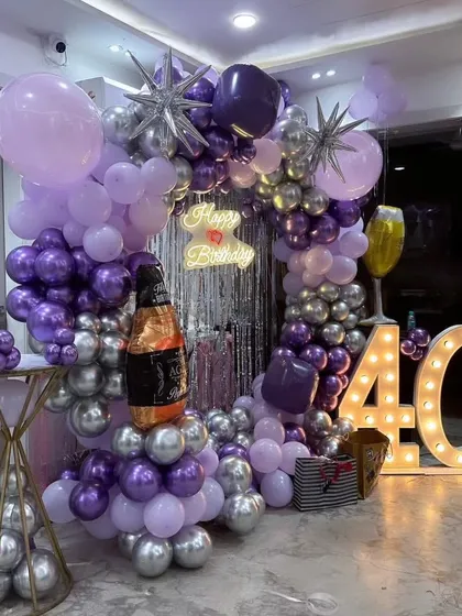 I designed this complete setup for a 40th birthday party. It includes a circular balloon arch, a silver fringe curtain, a custom neon sign, and large marquee numbers for a stylish photo backdrop.