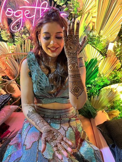 A close-up of the bride's hand, showing a beautiful mandala and architectural-inspired patterns on the arm.