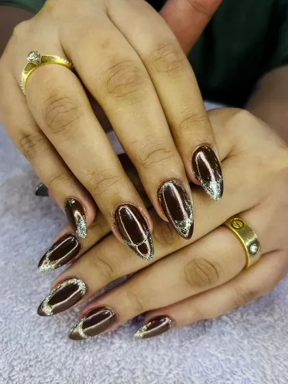A dark and elegant design with a deep brown cat eye polish and a sparkling silver glitter outline.