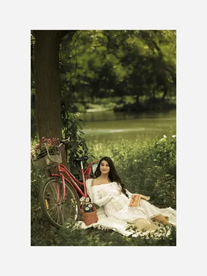 A joyful and relaxed portrait from the styled picnic. The mother-to-be smiles at the camera, surrounded by the beautiful, natural setting and charming props.