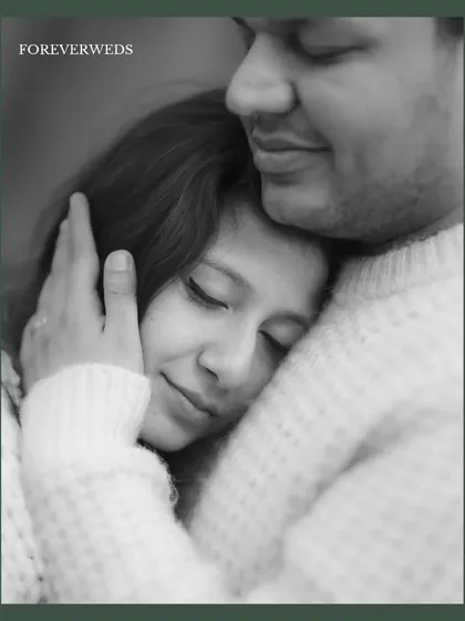 A close-up black and white portrait showing Sayantani resting peacefully in Piyush's embrace. This image conveys a profound sense of safety, comfort, and trust.