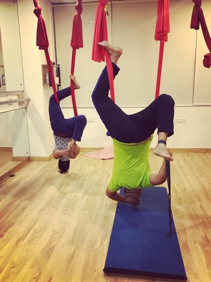 Two students explore an inverted pigeon pose. Even in a group class, everyone works at their own pace and level, modifying poses to suit their body.