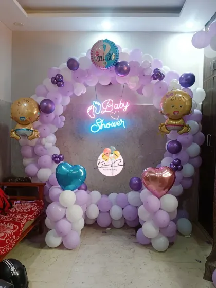 A lovely baby shower decoration in purple and white, featuring a heart-shaped balloon frame and a neon sign.