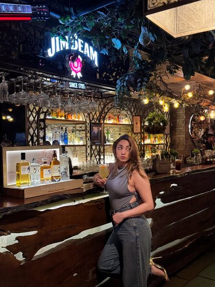 Holding a drink and posing at the bar. This is a classic lifestyle shot that works great for promoting venues or beverage brands.