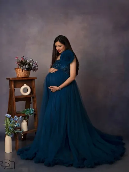 A quiet moment of connection, as she looks down at her bump. The simple studio setup allows her emotion to be the focus.