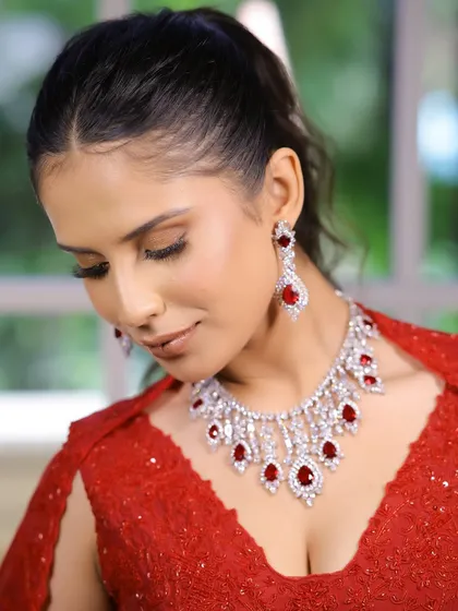 Embracing elegance in red with a touch of glamour. This close-up highlights the flawless base and soft bronze eyes, a perfect makeup look for a sangeet or cocktail party.