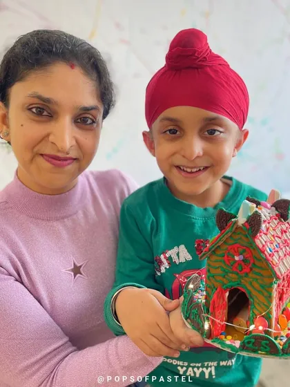 A mother and son duo with their wonderfully decorated gingerbread house, complete with fairy lights. A magical memory from our holiday event.