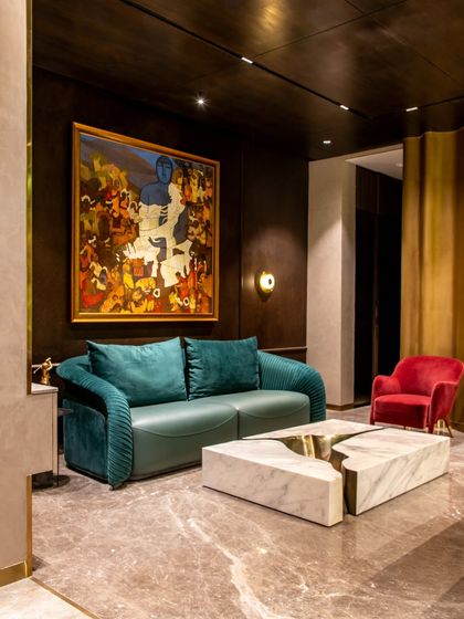 This angle highlights the curved gold wall that wraps around a seating nook in 'The Outhouse'. This feature adds a sculptural and glamorous element to the poolside lounge.