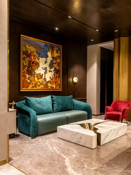 This angle highlights the curved gold wall that wraps around a seating nook in 'The Outhouse'. This feature adds a sculptural and glamorous element to the poolside lounge.