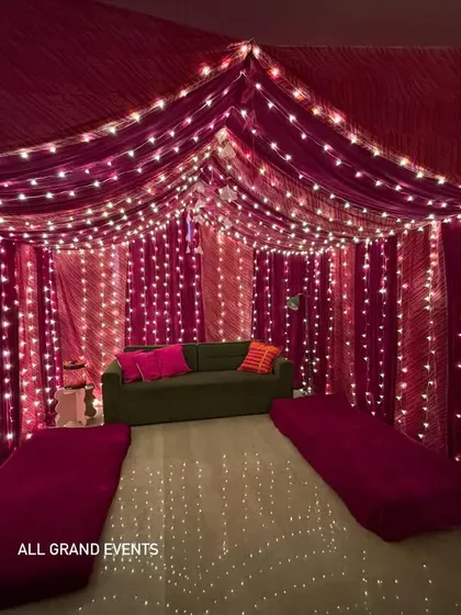I can transform your entire living room into a festive haven. Here, I've used rich magenta fabric to create a cozy tent-like canopy, with strings of fairy lights creating a magical, starry effect perfect for Diwali parties or home pujas.