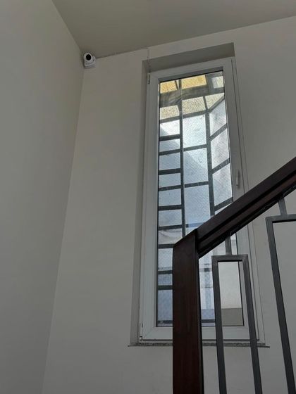 A discreetly placed camera in the corner of a stairwell. This strategic position allows for monitoring of movement between floors, a critical security measure for multi-level homes.