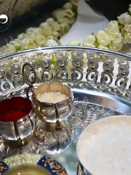 Details from a traditional 'Godbharai' or baby shower ceremony. An ornate silver tray holds sacred items like kumkum, rice, and a garland of fresh jasmine, all essential for the blessings.