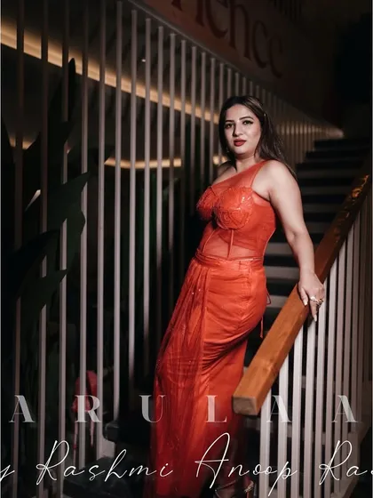 The gorgeous Kaavya Shah wearing a custom-designed red-orange draped saree with a corset-style bodice for a Christmas event.