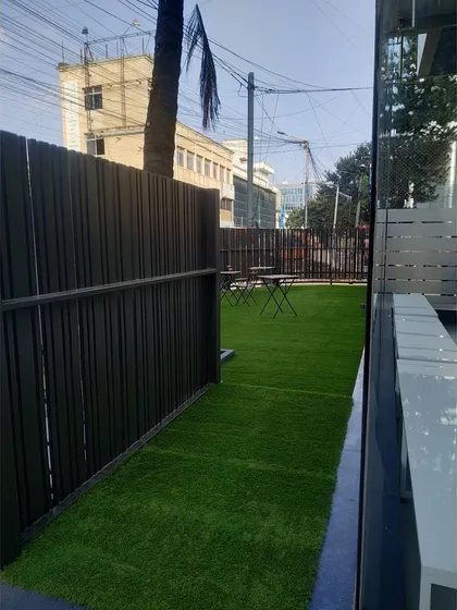 A view of the fenced outdoor space, designed to provide a private and secure area for the studio's clients. The slatted fence offers privacy while maintaining an open feel.