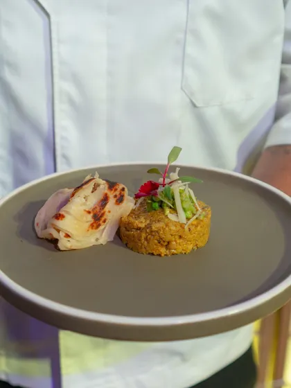 A modern interpretation of a classic dish, featuring a savoury cake of grains paired with a delicate, flaky paratha, garnished with fresh microgreens.