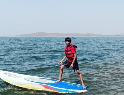 A young boy strikes a pose on his paddleboard, clearly enjoying his time on the water at Vani Vilas Sagara.