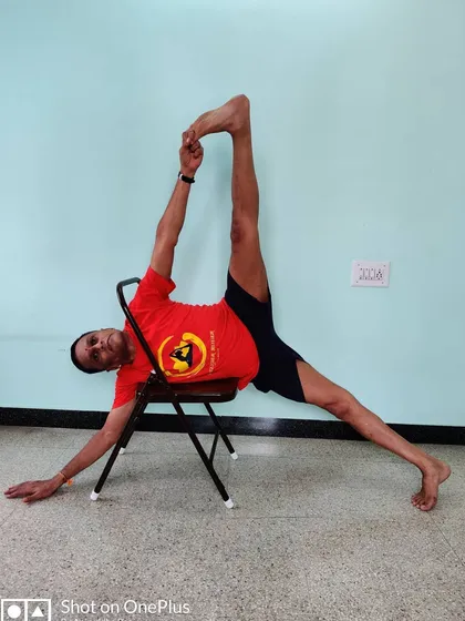 Vasisthasana (Side Plank Pose) with the leg lifted, using a chair for support. This builds oblique strength and balance, with the chair providing a stable foundation.