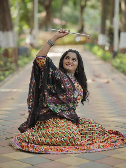 Ready for Dandiya. This pose with the dandiya sticks shows the fun and energy of the Navratri festival.