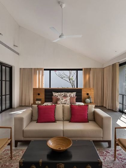 This spacious master bedroom in the Mango Orchard House opens up completely to the surrounding greenery. We designed the layout to include a separate seating area, creating a private suite for relaxation.