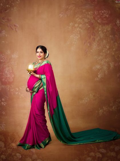 A portrait that celebrates the divine feminine. The mother-to-be, in a traditional pink and green saree, holds a golden 'kalash', a symbol of abundance and life.