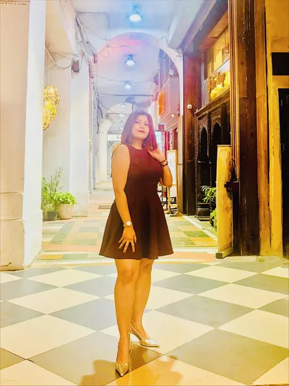 A full-length photo of my birthday outfit, a simple yet elegant dark-colored flare dress paired with silver heels, taken in a beautifully lit corridor.