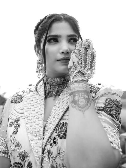 A stunning black and white shot of our client's Mehendi look. The intricate details of her colorful stone choker and hand harness stand out, showcasing the beautiful craftsmanship.