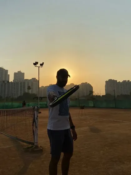 Pointing my racket towards the camera against the sunset. My promise is to guide you, push you, and support you, but your journey is yours to own.