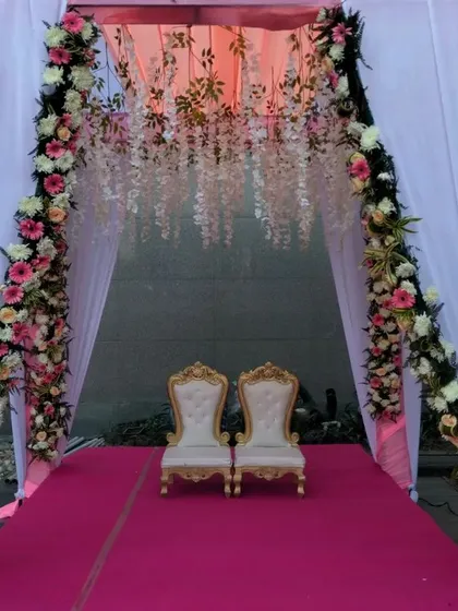 A lovely seating area for the couple, framed by a floral arch and hanging white flower strings. This makes for a perfect photo spot during the wedding.