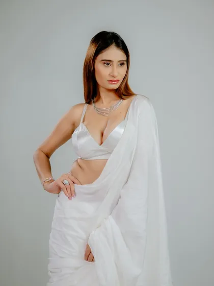A profile-oriented pose that showcases the complete look, from the layered necklace to the flow of the saree. The simple setting makes the subject pop.