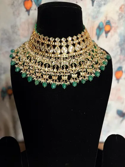 An ode to timeless elegance. This Kundan choker with green pearl drops is a magnificent piece that adds a touch of royalty to your wedding attire.