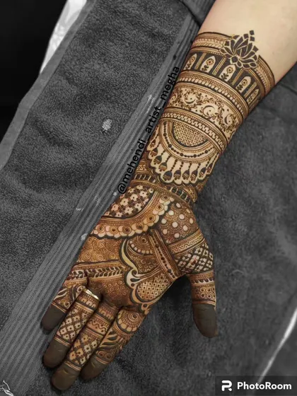 A single arm showcasing a detailed design with jewellery-like elements, paisleys, and a lotus cuff, demonstrating a full bridal arm pattern.