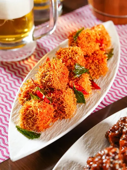 Crispy fried appetizers served on a white platter, with a mug of beer in the background. This shot captures the perfect pairing for an Oktoberfest celebration.