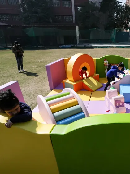 A wide shot showing kids enjoying every corner of the play area, from the tunnel to the climbers.