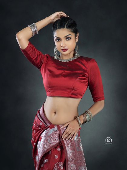 A close-up of the Indo-western fusion look, focusing on the model's pose and the contrast between the red saree and modern styling. The dark background makes the colors pop.