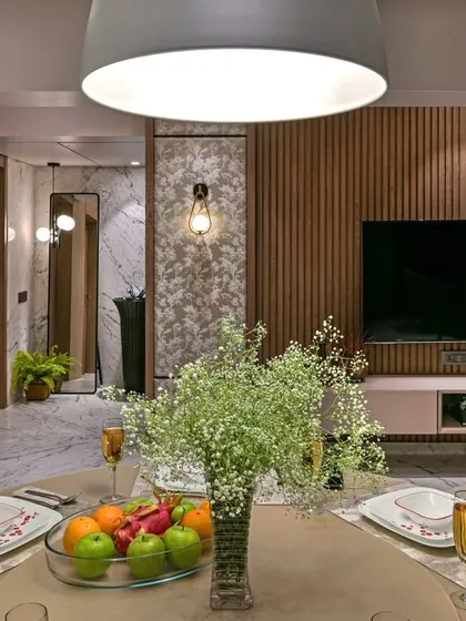 A cozy dining setup that overlooks the living area. The fluted wood paneling behind the television adds warmth and texture, creating a visual link between the dining and lounging zones.