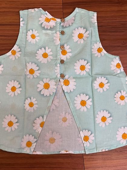 The back of our mint green sunflower top, showing the cute open-back design and wooden button details. It's these little touches that make an outfit special.