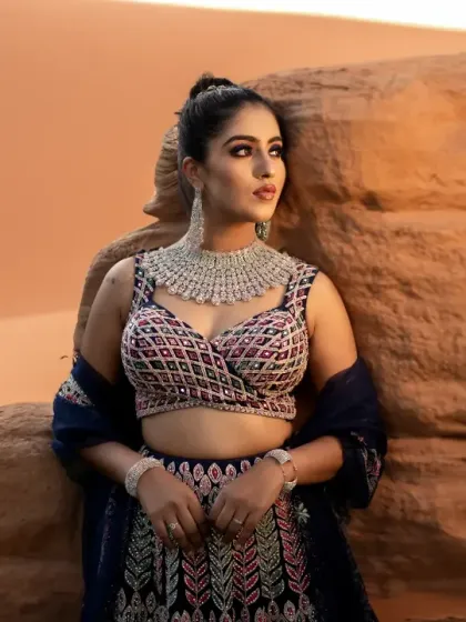 A stunning bridal portrait set against a warm, desert-like backdrop. The bride's powerful pose and the rich colors of her outfit create a bold and beautiful image.