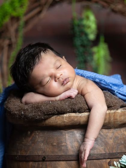 A simple and rustic portrait of a newborn sleeping on a wooden barrel.