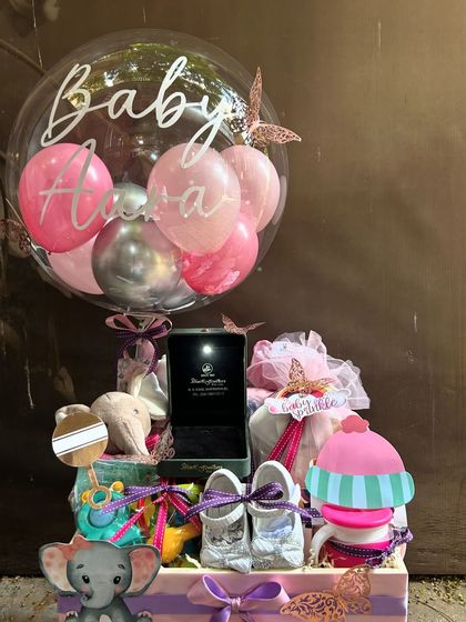A truly personalized welcome for baby Alora. This hamper is filled with carefully selected gifts, including tiny shoes and toys, and is topped with a custom bubble balloon featuring her name. The butterfly details add a whimsical finishing touch.