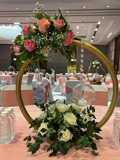 A modern and chic centerpiece featuring a golden ring, floral arrangements, and a hanging glass orb for a candle. This design is perfect for a contemporary wedding.