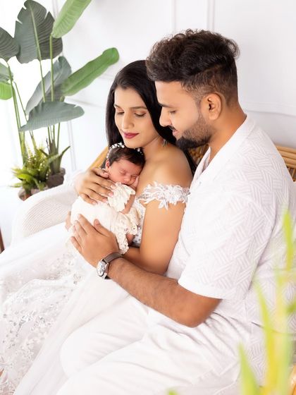 A beautiful family portrait with their newborn baby. The all-white outfits and the parents' gentle embrace create a pure and angelic feel.