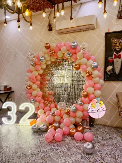 A stylish 32nd birthday party with a pink, cream, and rose gold balloon ring, a shimmer backdrop, and a marquee number '32'.