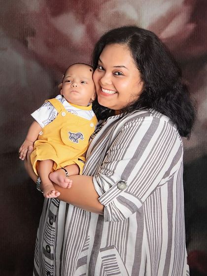 A happy mother holding her adorable baby boy. The floral backdrop adds a touch of softness to this classic mother and child portrait.