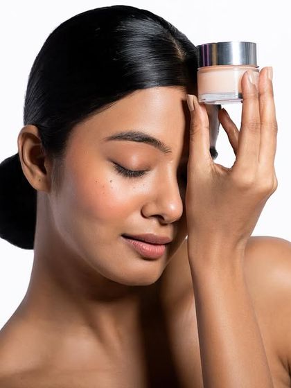 This pose creates a connection between the model and the skincare product. The focus is on the feeling of the product, conveyed through the model's serene expression. The lighting is soft and flattering, emphasizing a natural, healthy glow.