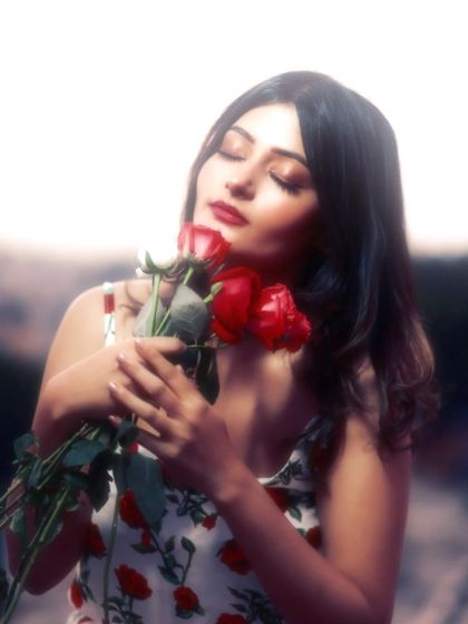 A dreamy, soft-focus portrait with a romantic feel. The way she holds the roses, combined with the ethereal glow, creates a picture of pure poetry.