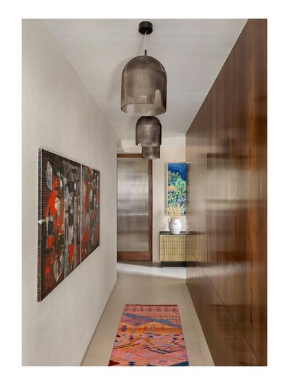 This hallway in the House of Terraces features a wall of rich, polished wood paneling. The warmth of the wood is balanced by a colorful rug and contemporary art.