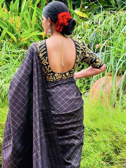 A back view of the client in the black checked saree, showing the deep U-back and intricate gold embroidery of the blouse.