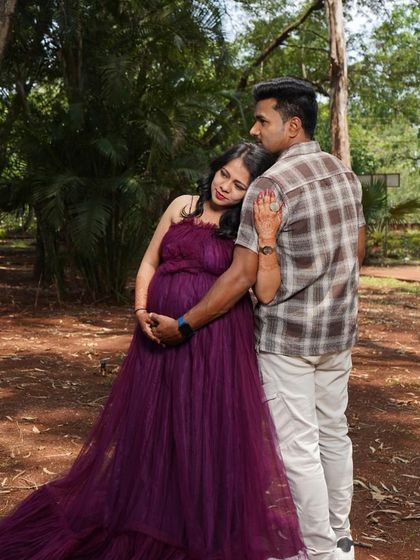 A romantic couple's pose during a maternity shoot in the woods. The deep purple of the gown adds a touch of richness and intimacy to the scene.